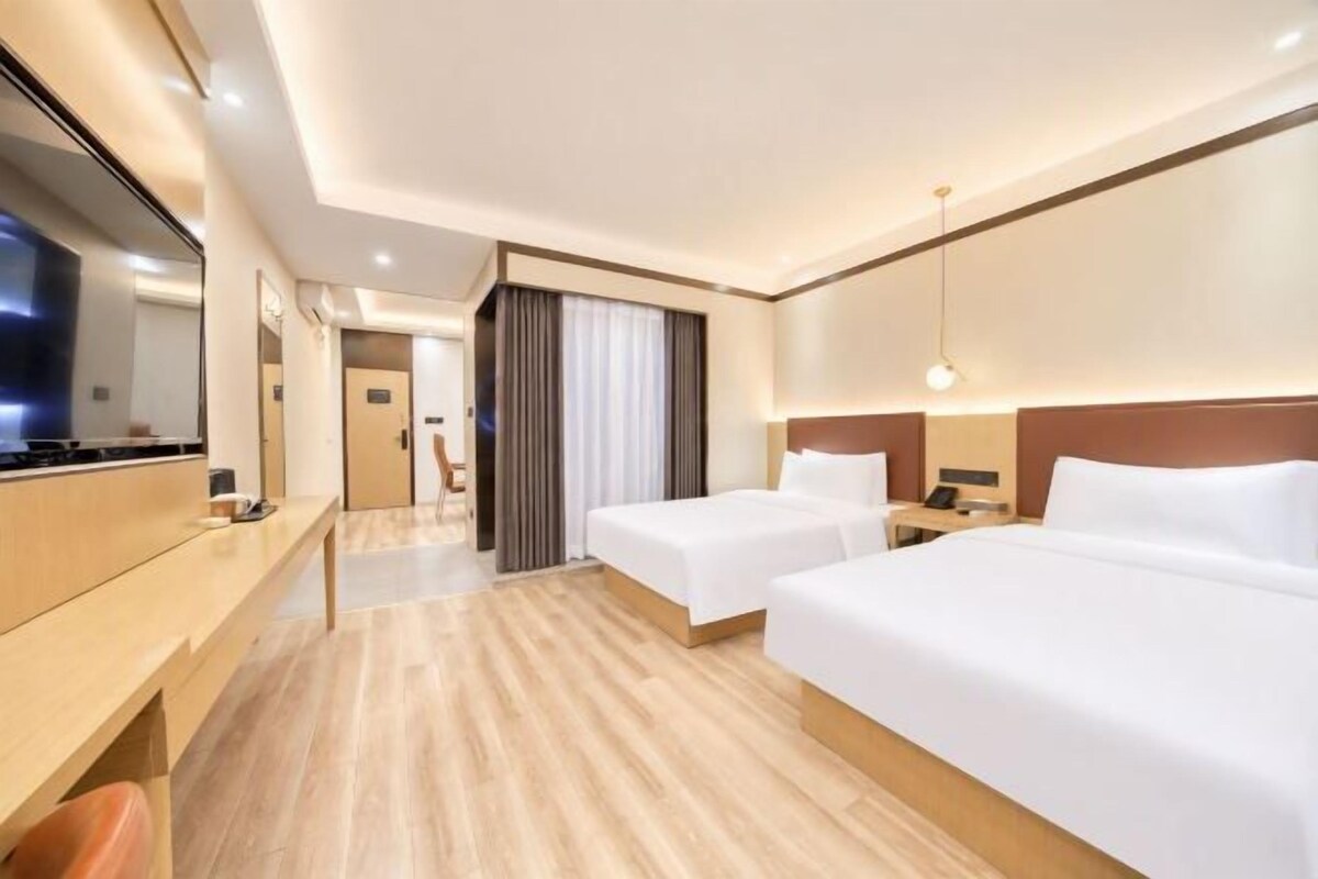 Hotellihuone, jossa on kaksi sänkyä, työpöytä, televisio ja taustalla näkyvä kylpyhuone.