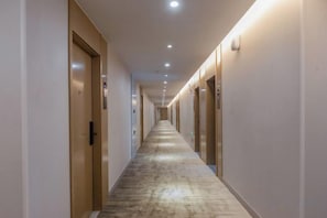 A hotel corridor with doors on both sides, a carpeted floor, and recessed lighting. - GYA Hotel (Jiaxing Nanhu Scenic Area Nanhu Tiandi) (Jiaxing)