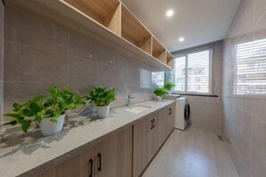 A modern kitchen with a long countertop, built-in cabinets, and potted plants. - GYA Hotel (Jiaxing Nanhu Scenic Area Nanhu Tiandi) (Jiaxing)
