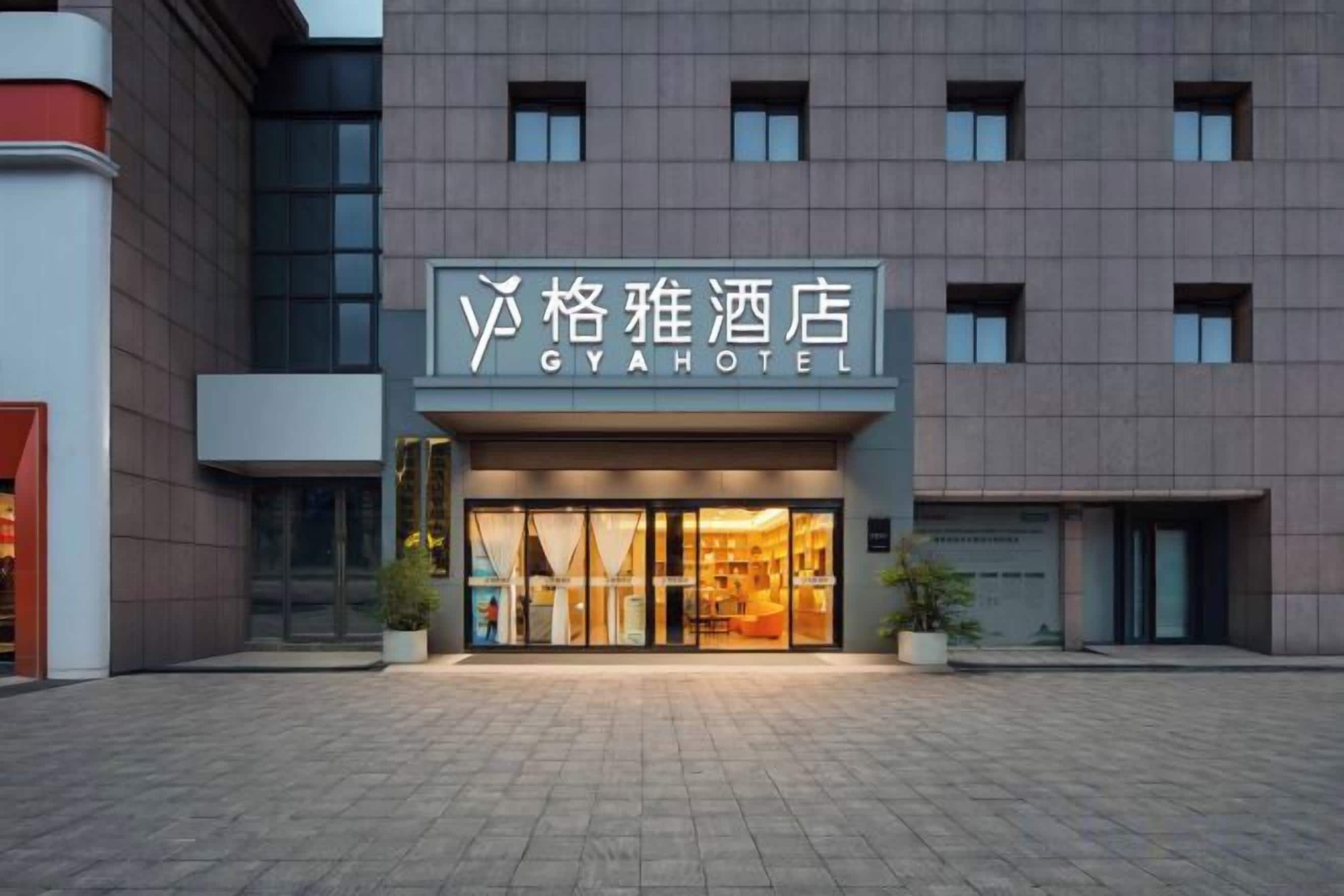 Entrada de un hotel con un cartel que dice 'GYA HOTEL' y una fachada de edificio moderna.