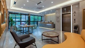 A modern hotel lobby with a reception desk, seating area, and an elevator. - GYA Hotel (Jiaxing Nanhu Scenic Area Nanhu Tiandi) (Jiaxing)