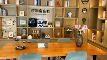 A room with a wooden table, chairs, a bookshelf, and a decorative vase with flowers.