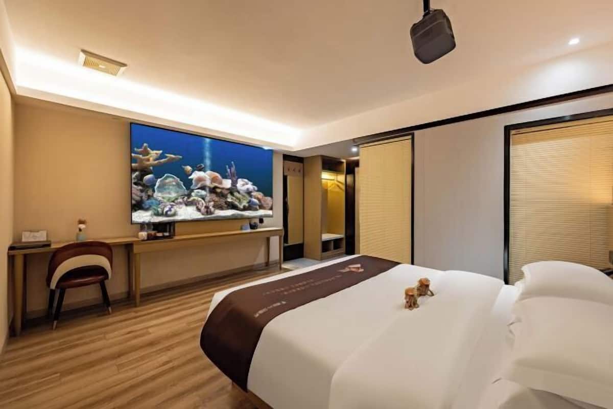 A hotel room with a bed, a desk, a chair, a television, and a large window.