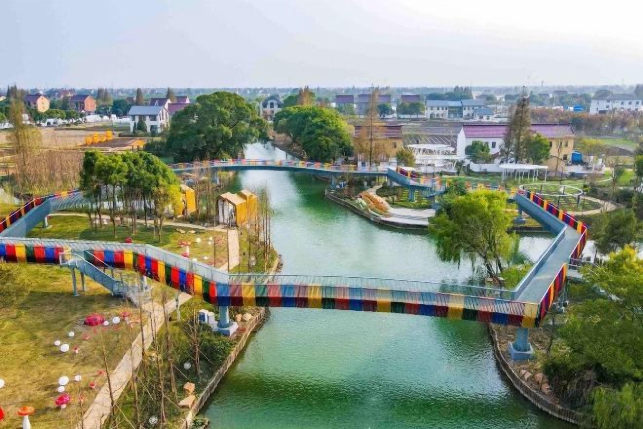 A bridge over a river with a park and buildings in the background.