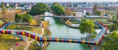 A bridge over a river with a park and buildings in the background.