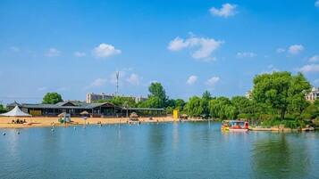 A lake with a boat, buildings, and trees in the background.