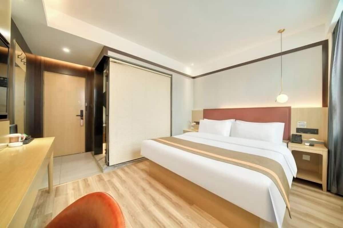 A hotel room with a bed, bedside table, and a desk with a chair.