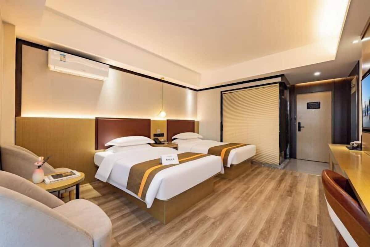 A hotel room with two beds, a desk, a chair, and a minibar.