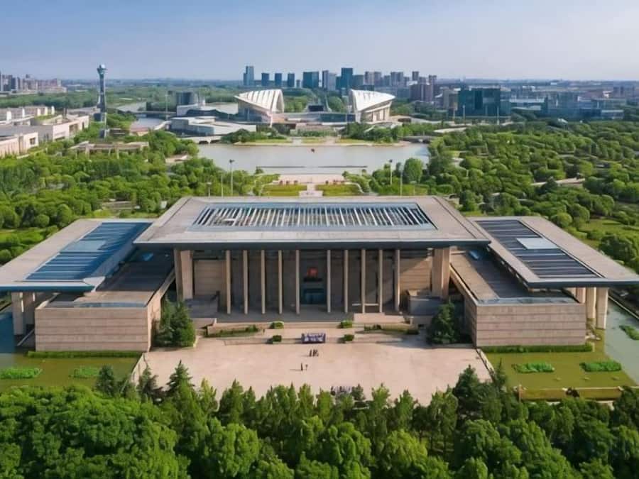 A large, modern building with a central courtyard, surrounded by greenery and water features.