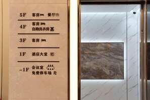 A hotel interior with a marble wall and a door with a window. - GYA Hotel (Jiaxing Nanhu Scenic Area Nanhu Tiandi) (Jiaxing)