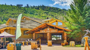 Eine Lodge mit Holzfassade, einem Schild mit der Aufschrift "Snow Park Lodge" und einer Statue eines Skifahrers.