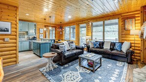 Ein Holzblockhaus-Interieur mit Wohnzimmer, Küche und Essbereich.