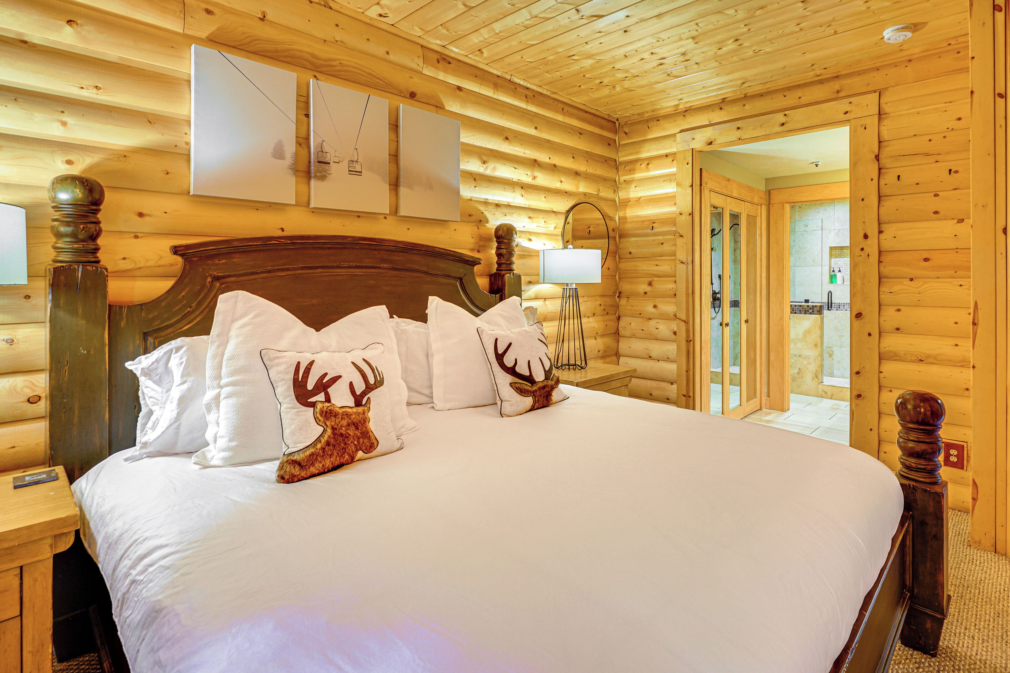 Un dormitorio de cabaña de madera con una cama grande, cabecera de madera y un espejo sobre la cama.