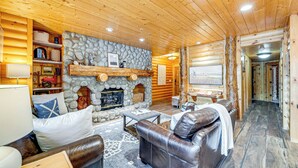 Ein Blockhaus-Interieur mit Kamin aus Stein, Ledersofas und Holzwänden.