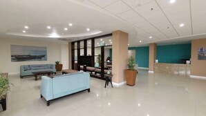 Un hall d’entrée spacieux, avec un canapé bleu clair, un comptoir d’accueil et un grand tableau accroché au mur.