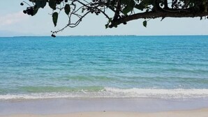 Une plage avec une eau d’un bleu limpide et un rivage sablonneux.