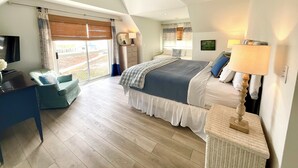 A bedroom with a bed, bedside lamps, a dresser, a desk, and a large window with curtains. - Gorgeous/Great Gulf Views! (Gulf Shores)