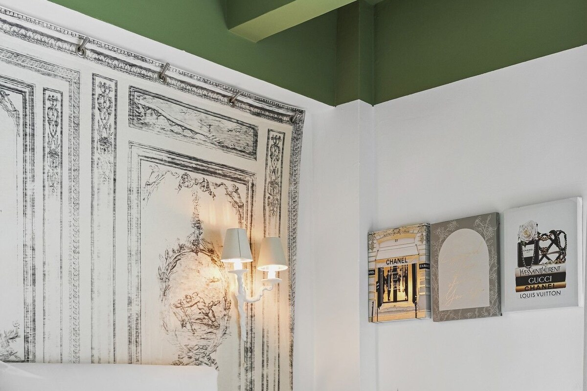 Quarto com uma cama grande, cabeceira com painel decorativo e luminárias fixadas na parede.