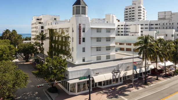 Un hôtel doté d’une tour imposante, offrant une vue sur le front de mer et situé sur une rue appelée Collins Avenue.