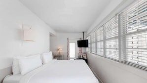 Une chambre d’hôtel avec un grand lit, un téléviseur à écran plat et une fenêtre équipée de stores.