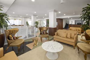 A spacious lobby with a reception desk, a sofa, chairs, and a marble coffee table.