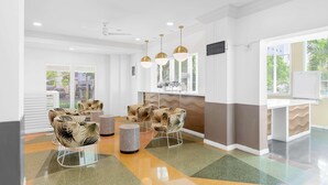 A modern waiting area with comfortable chairs, a white reception desk, and a large window with a view of greenery.