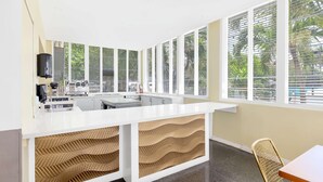 A modern kitchen with a white countertop, built-in appliances, and large windows with blinds.