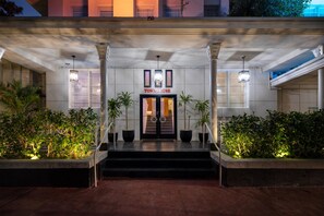 Entrada de un hotel con un letrero que dice 'TOWNEHOUSE', escalones que conducen a la puerta y macetas a ambos lados.