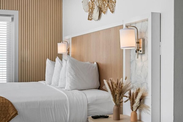 A hotel room with a bed, bedside lamps, a remote control, and decorative wall art.