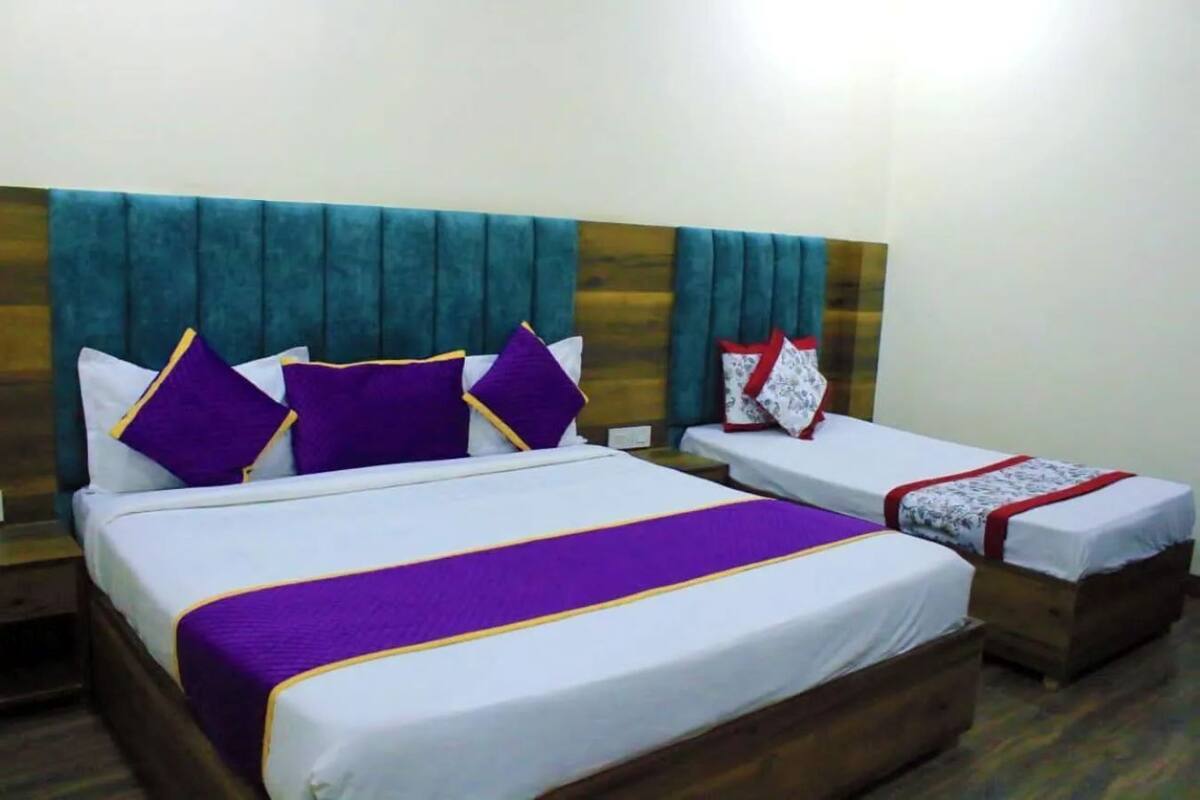 A hotel room with a large bed, a smaller bed, and a nightstand.