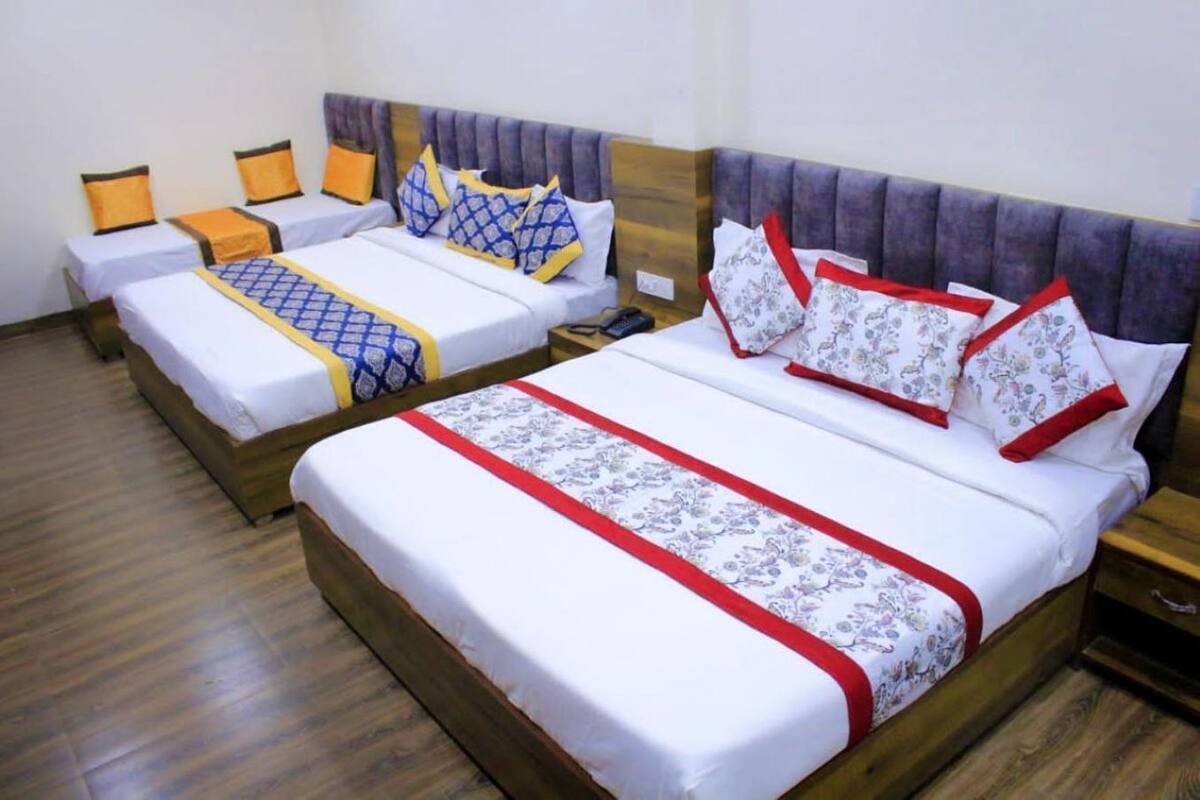 A hotel room with two single beds, each with a wooden headboard, white bedding, and decorative pillows.