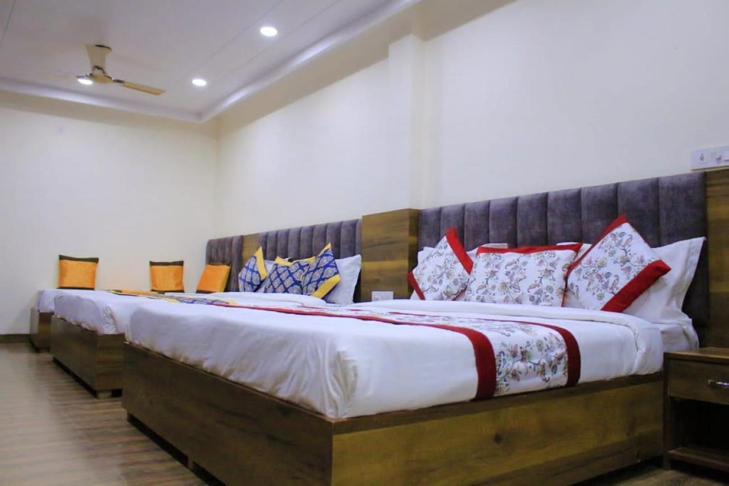 A hotel room with two beds, wooden headboards, and a ceiling fan.