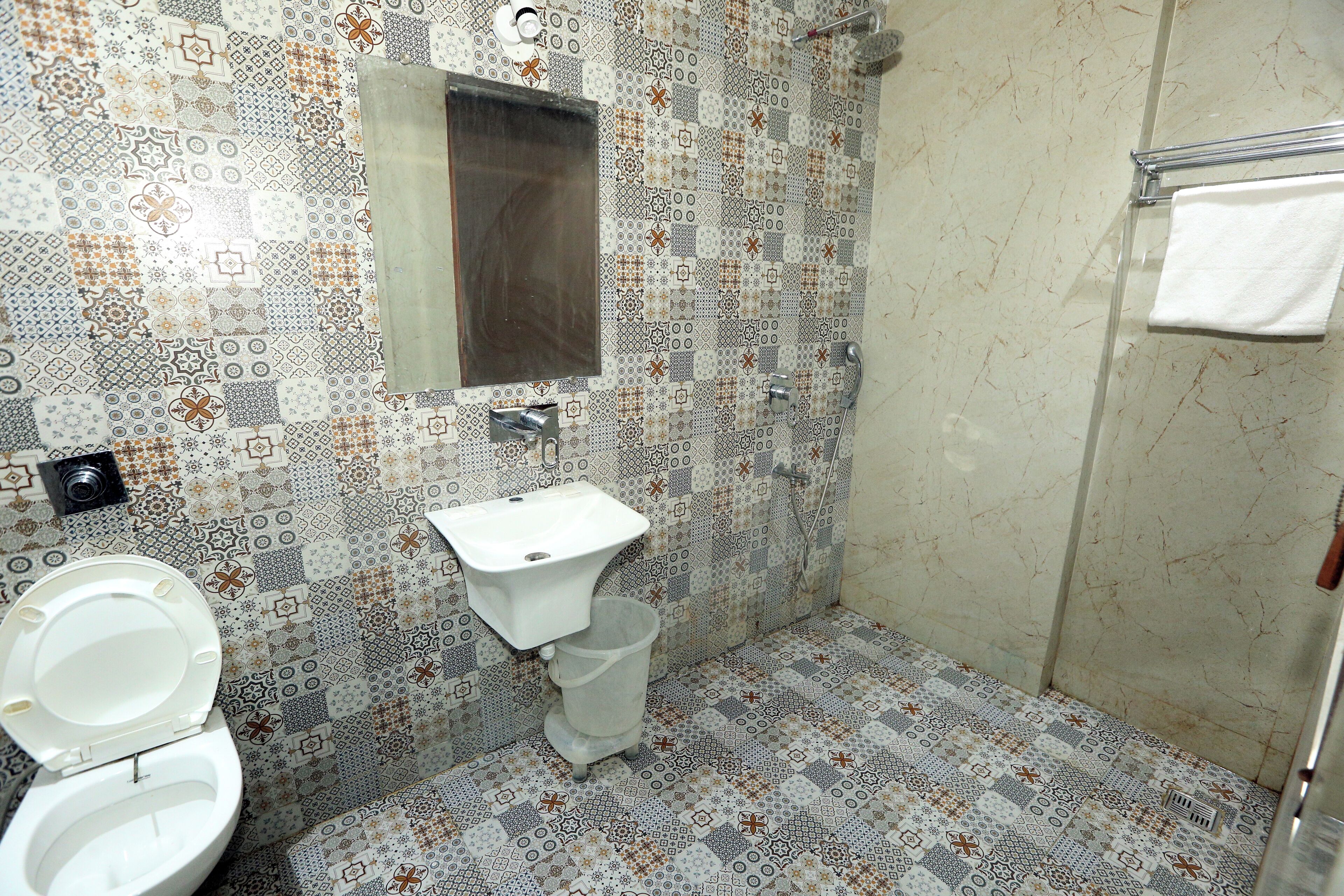Um banheiro com piso de azulejos estampados, uma pia branca e um espelho sobre ela.