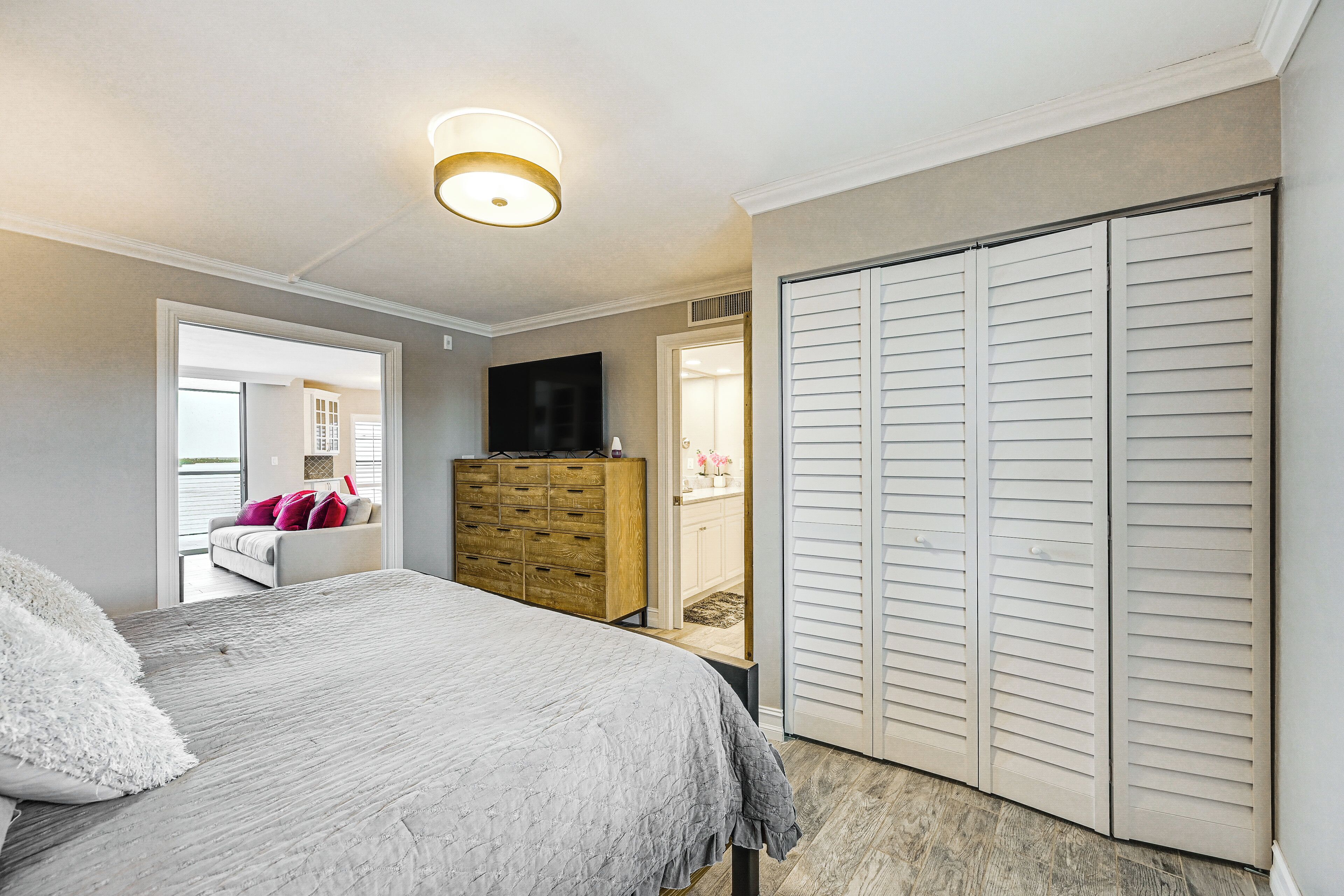 Une chambre à coucher avec un lit, une commode, une télévision et un placard.