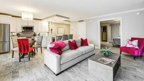 Una sala de estar moderna con un sofá gris, cojines rojos y blancos, una mesita de centro y una silla roja.