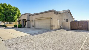 A two-story house with a garage, a gravel driveway, and a large tree to the left. - Hot Tub & On-site Hiking: Phoenix Retreat! (Phoenix)