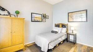A bedroom with a bed, a nightstand, a wooden wardrobe, and wall art. - Hot Tub & On-site Hiking: Phoenix Retreat! (Phoenix)