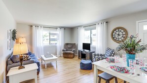 Una sala de estar con sofá, sillón, mesa de centro y mesa de comedor dispuesta para una comida.