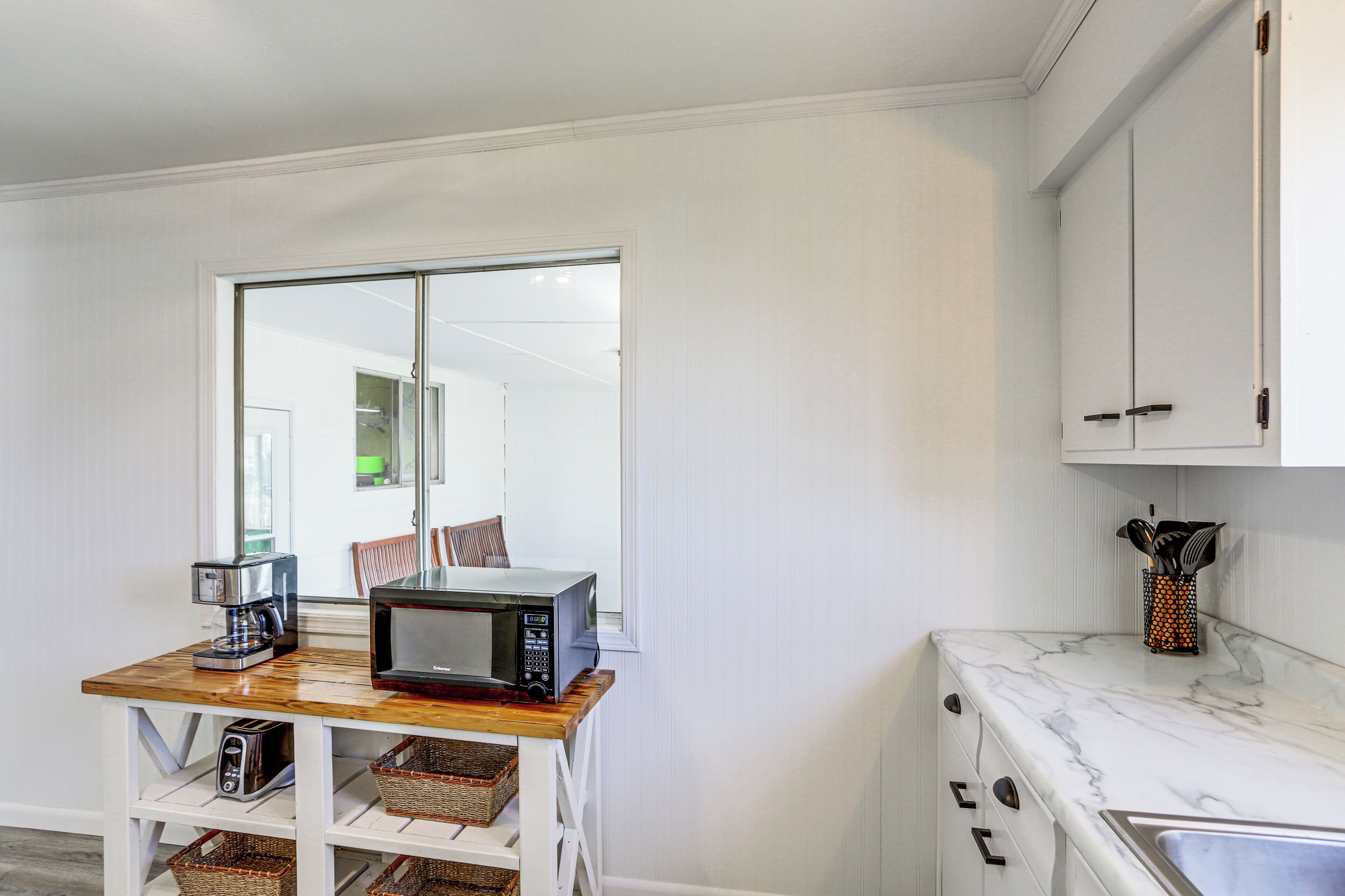 A kitchen with a wooden table, a microwave, a coffee maker, and a sink.