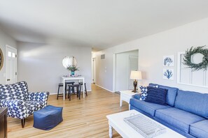 A living room with a blue sofa, a patterned armchair, a coffee table, and a dining area with a white table and chairs. - Waterfront Port Clinton Cottage: 5 Mi to Lake Erie (Port Clinton)