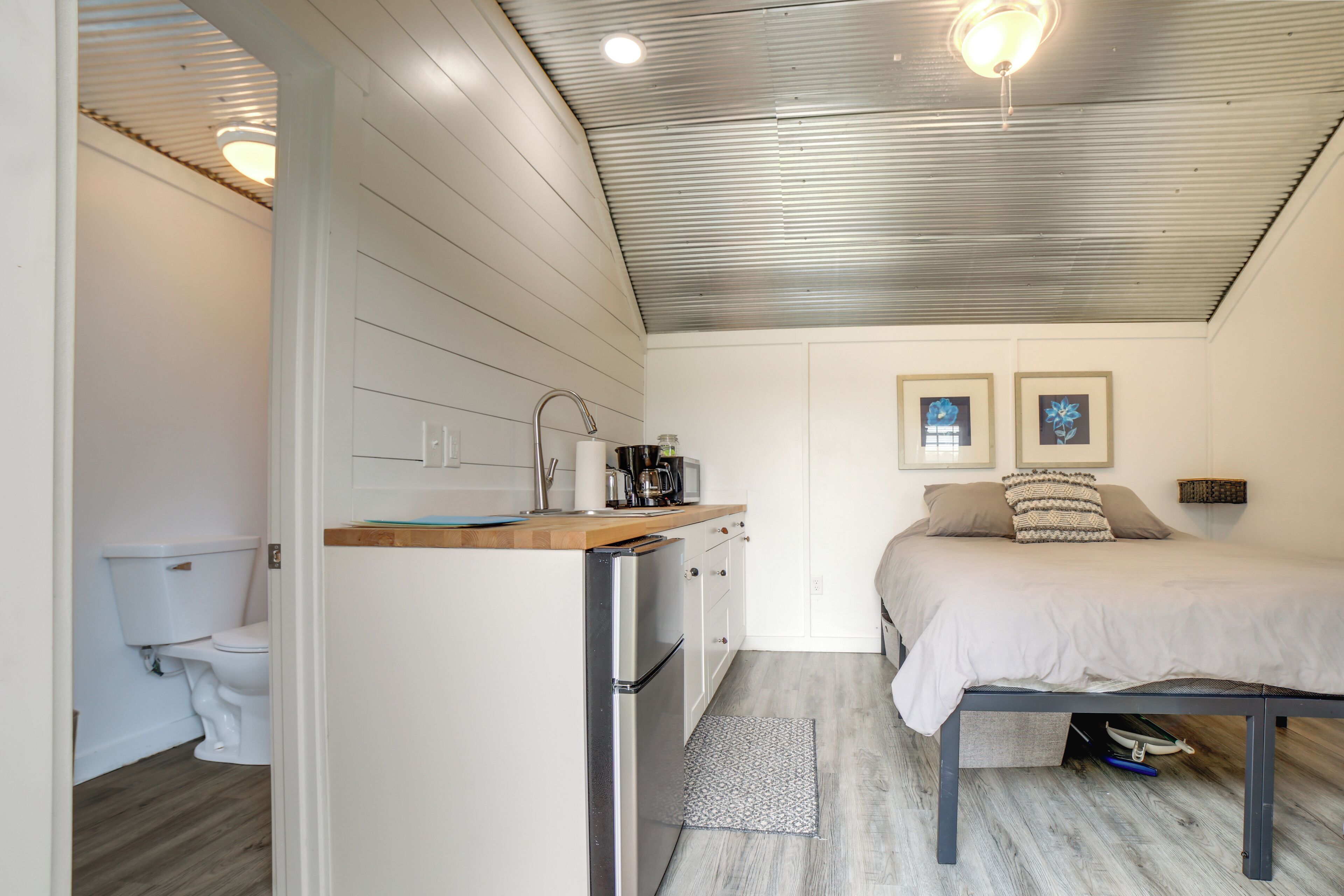 A compact room with a kitchenette, a bed, and a small bathroom.