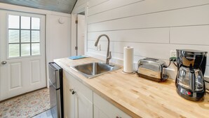 Una cucina con lavandino in acciaio inossidabile, un tostapane e una macchina del caffè su un piano di lavoro in legno.