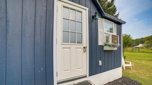 Una casa con la porta d'ingresso bianca, un tappetino d'entrata e un piccolo portico.