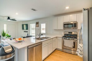 Una cocina moderna con armarios blancos, electrodomésticos de acero inoxidable y suelo de madera.