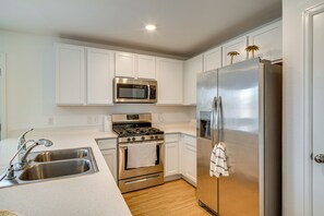 Una cocina moderna con armarios blancos, electrodomésticos de acero inoxidable y piso de madera.