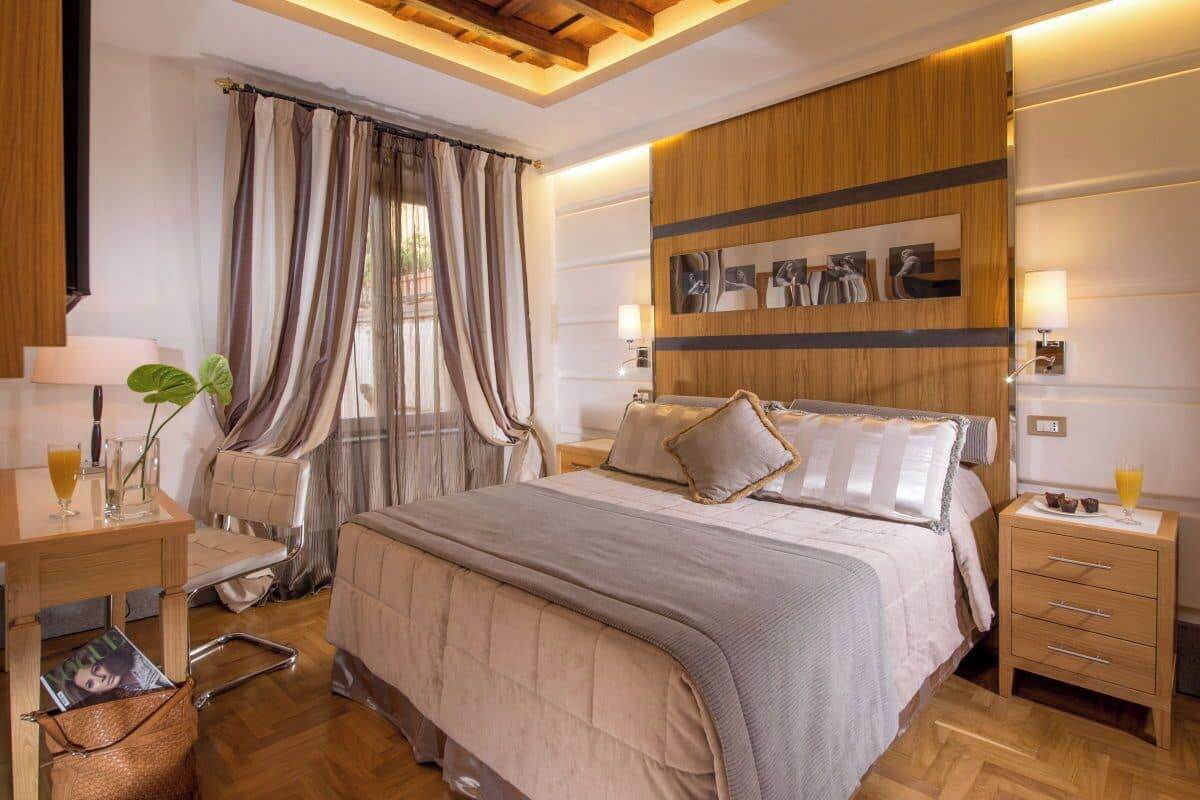 Un dormitorio moderno con una cama grande, mesitas de noche, un escritorio y una ventana con cortinas.