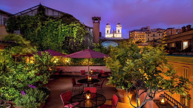 An outdoor patio with round tables and chairs, surrounded by lush greenery and potted plants. - The Inn at the Spanish Steps Exclusive Collection - Roberto Di Rienzo (Rome)