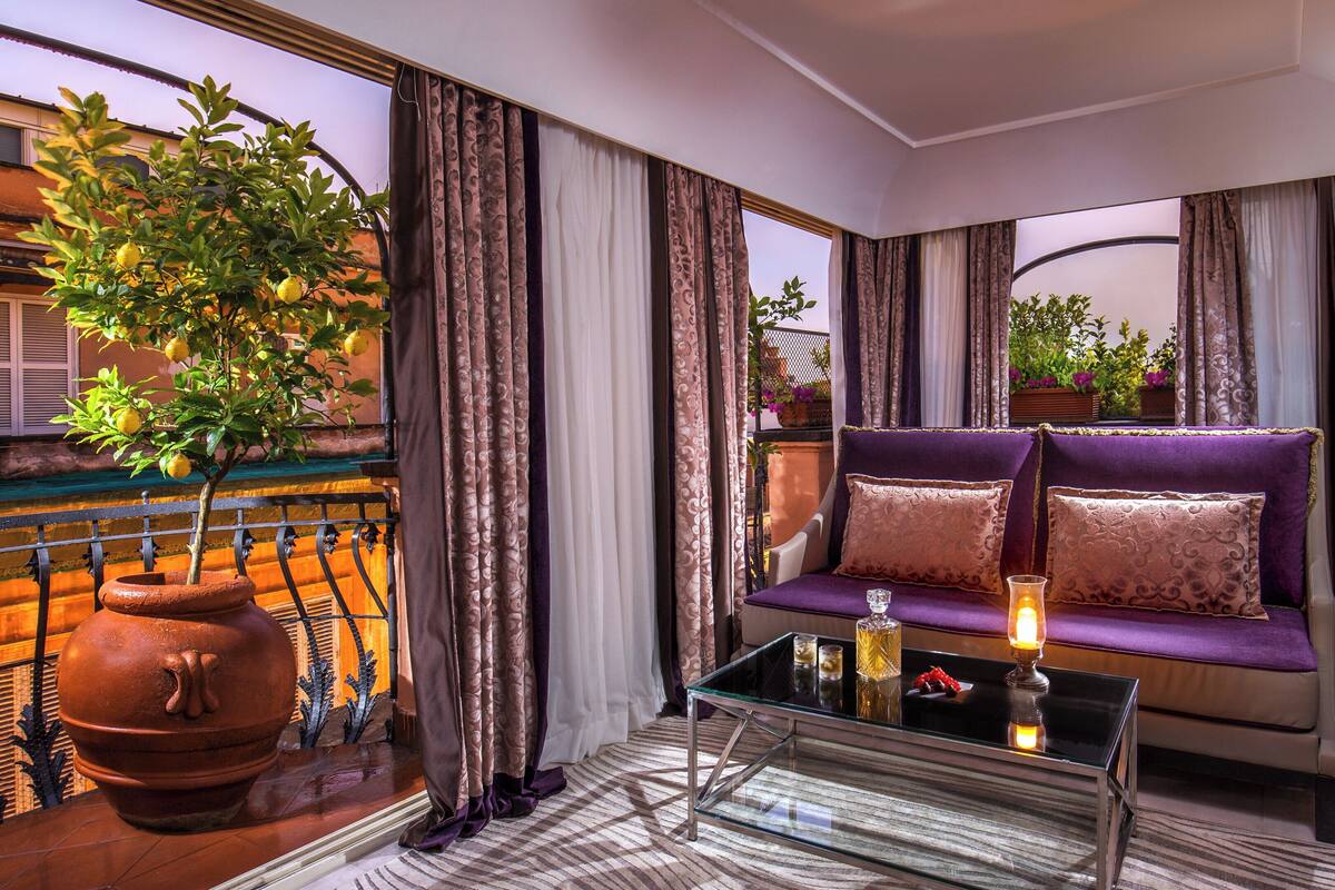 Una sala de estar moderna con un sofá morado, una mesa de centro de vidrio y una planta en maceta.