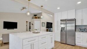 A modern kitchen with white cabinetry, stainless steel appliances, and pendant lighting.