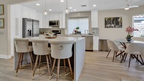 A modern kitchen with white cabinetry, stainless steel appliances, and a central island with bar stools.